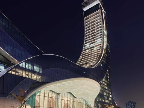 a tall building at night with its lights on at Raffles Doha in Doha