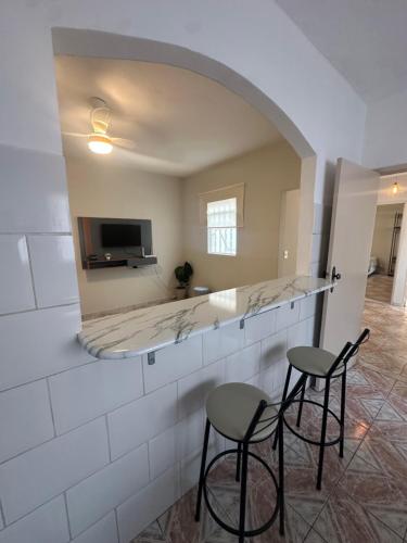 a kitchen with two stools and a counter with a mirror at Apartamento no centro de Aparecida in Aparecida