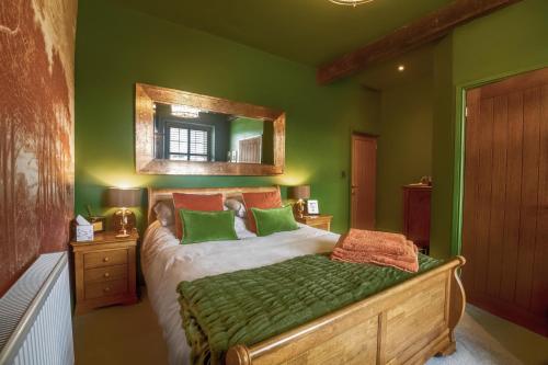 a bedroom with a bed with green walls and a mirror at Westfield House in Gargrave