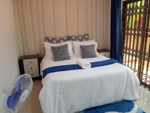 a bedroom with a white bed with a fan at 3 bdr apartment with Solar Backup & Wi-Fi Salama in Lusaka