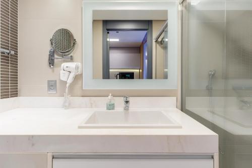 a bathroom with a white sink and a mirror at 1164 Helbor Stay Batel, Conforto e Estilo no Coração de Curitiba in Curitiba