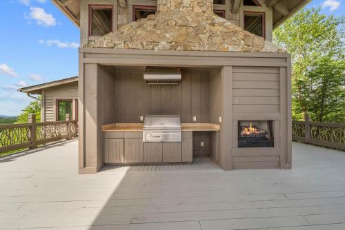 an outdoor kitchen with a fireplace on a deck at Overlook at Wilderness Trail in Newland