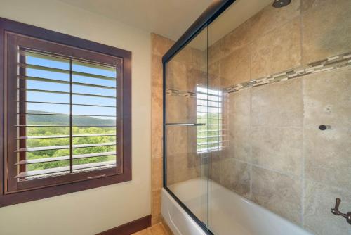 a bathroom with a shower and a tub and a window at Overlook at Wilderness Trail in Newland