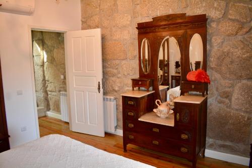ein Schlafzimmer mit einer Kommode und einem großen Spiegel in der Unterkunft Castelo Gerês - Exquisite Eco-Cottage - jacuzzi in Lindoso