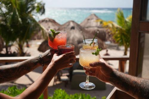 a group of people holding up drinks in front of the beach at Paamul Hotel in Paamul