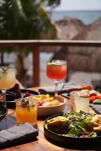 a wooden table with plates of food and drinks at Paamul Hotel in Paamul