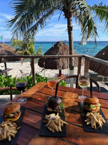 a wooden table with two sandwiches and glasses of wine at Paamul Hotel in Paamul