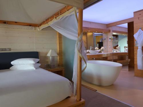 une chambre avec un grand lit et une baignoire dans l'établissement Movenpick Resort Lamantin Saly, à Saly Portudal