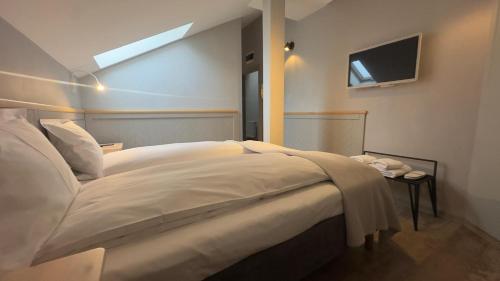 a bedroom with a large white bed and a tv at Villa Piazzetta in Bacău