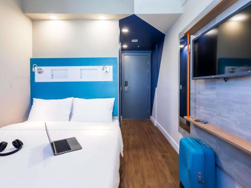a hotel room with a bed with a laptop on it at ibis budget Pindamonhangaba in Pindamonhangaba