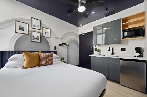 a bedroom with a white bed and a kitchen at The Neon Elm Hotel in San Diego