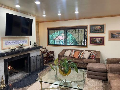 Una sala de estar con chimenea y televisión. en Casa del Bosque - Hermosa y Cálida Cabaña en Huitzilac - 22 huéspedes, en Huitzilac