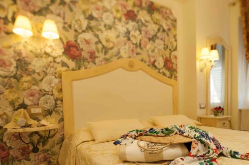 a bedroom with a floral wallpaper with a bed with a purse on it at Hotel Astigiana & Appartamenti in Varazze