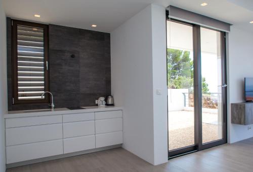 a kitchen with white cabinets and a large window at Soho Apartments Brela in Brela