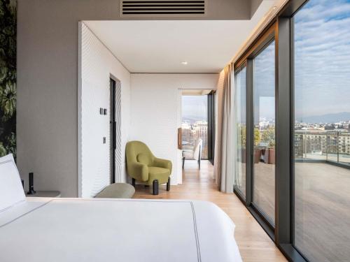 a bedroom with a white bed and a balcony at Swissôtel Tbilisi in Tbilisi City