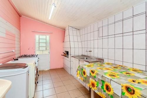 a kitchen with a sink and a table in a room at Casa Rosa Charmosa Completa BC Churrasco & Garagem in Balneário Camboriú