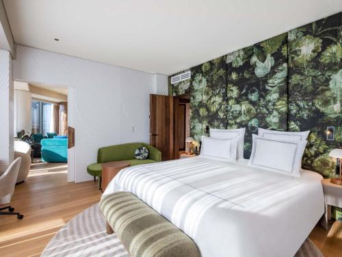 a bedroom with a large white bed and a green wall at Swissôtel Tbilisi in Tbilisi City