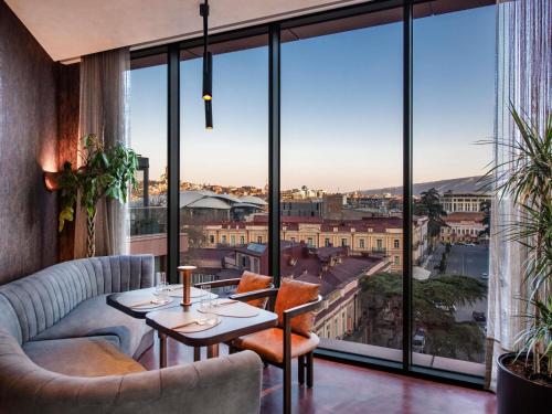 a room with a table and chairs and large windows at Swissôtel Tbilisi in Tbilisi City