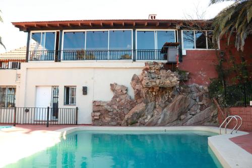 a house with a swimming pool in front of a building at Costa Bonita Aparts & Spa in Villa Carlos Paz