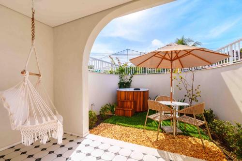 eine Terrasse mit einer Hängematte und einem Tisch mit einem Sonnenschirm in der Unterkunft Santé Vivre L'Experience by Livá OFICIAL in Búzios