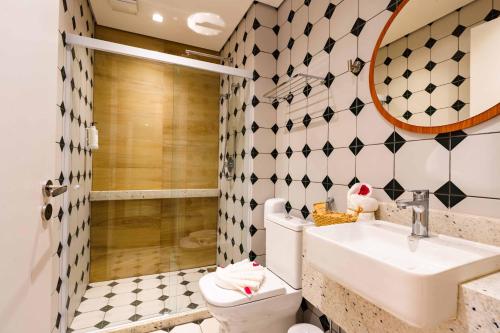 a bathroom with a sink and a toilet and a mirror at Santé Vivre L'Experience by Livá OFICIAL in Búzios