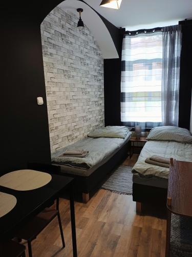 a bedroom with two beds and a brick wall at Rajca Room's - Pokoje przy Jasnej Górze in Częstochowa