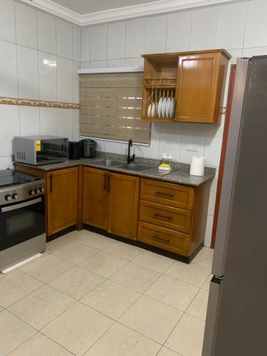 a kitchen with wooden cabinets and a stainless steel refrigerator at Cozy and Comfortable 2 bedroom for Families Home-away near Airport in Accra