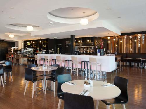 a restaurant with tables and chairs and a bar at BreakFree on Cashel, an Accor Hotel in Christchurch