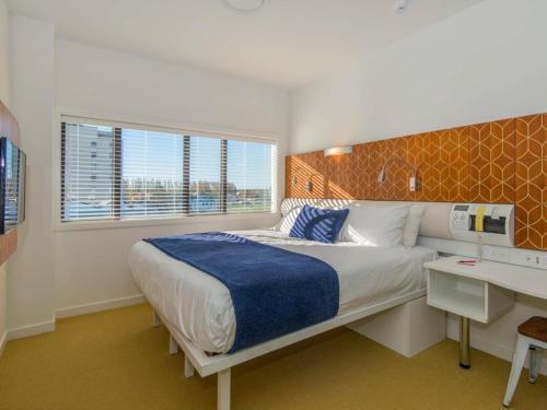a bedroom with a bed with a desk and a window at BreakFree on Cashel, an Accor Hotel in Christchurch