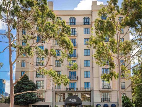 a building with trees in front of it at Mantra on Jolimont Melbourne in Melbourne