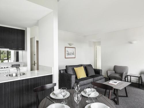 a living room with a couch and a table at Mantra on Jolimont Melbourne in Melbourne