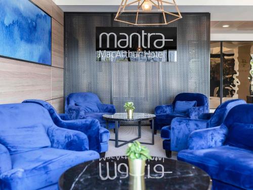 a room with blue chairs and a table and a sign at Mantra MacArthur Hotel in Canberra