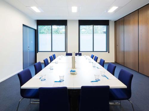 a large conference room with a long table and blue chairs at Mantra MacArthur Hotel in Canberra