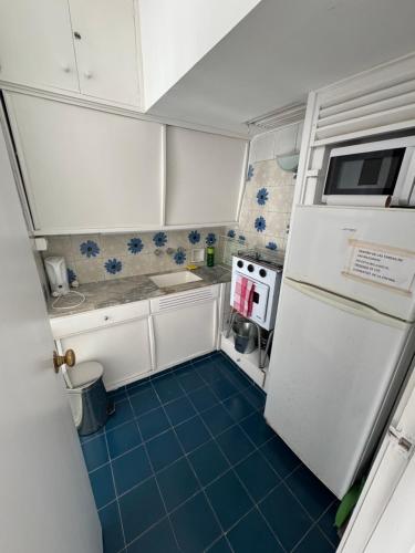 une petite cuisine avec un réfrigérateur blanc et un sol bleu dans l'établissement Amenidades y terraza vista mar, à Punta del Este