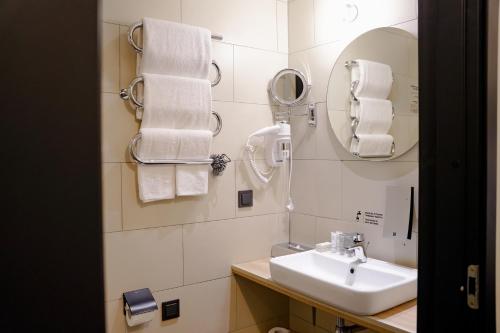 a bathroom with a sink and a mirror and towels at Loop Hotel Vilnius in Vilnius