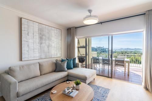 BRAND NEW Luxury Apartment with Ocean View في بليتنبيرغ باي: غرفة معيشة مع أريكة وطاولة