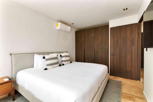 a bedroom with a large white bed and wooden cabinets at Stylish 1BR Condo with Private Pool & Balcony in Tulum