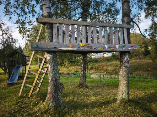 a wooden bench in a tree with a ladder at Kořenov 10 chalupa na horách in Kořenov