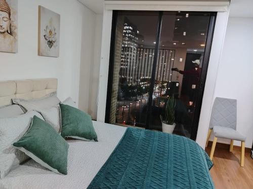 a bedroom with a bed with green pillows and a window at Premium Tranquility in the International Center in Bogotá