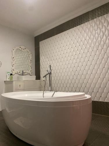 a large white tub in a bathroom with a mirror at Stone Guesthouse in Gaborone