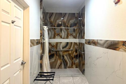 ヒューストンにあるHotel O Regency Suites Houston - IAH Beltway 8の大理石の壁のバスルーム(シャワー付)