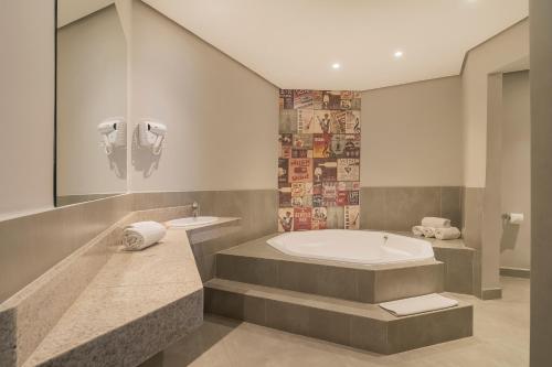 a bathroom with a tub and a sink at ibis Styles Sorocaba Santa Rosalia in Sorocaba