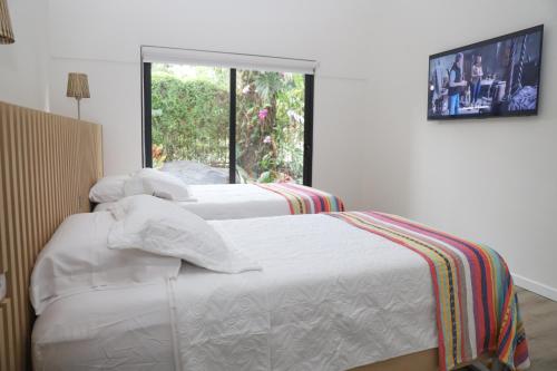 two white beds in a room with a window at Hotel Colina Inn Escazu in San Rafael