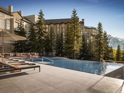 a hotel with a swimming pool in front of a building at Rimrock Banff, Emblems Collection in Banff