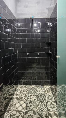 a bathroom with a black tiled shower with a tile floor at Hostal KEMMM in Mexico City
