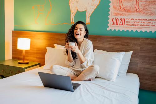 a woman sitting on a bed with a laptop at ibis Styles Sorocaba Santa Rosalia in Sorocaba