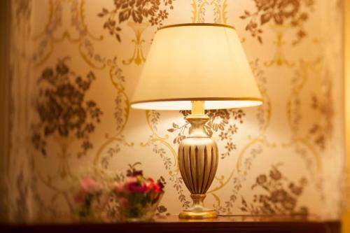 a lamp sitting on top of a table with flowers at Hotel Astigiana & Appartamenti in Varazze