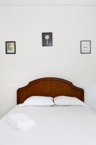 a bed with two pillows and three pictures on the wall at Hotel Villa Ivel in Turbaco