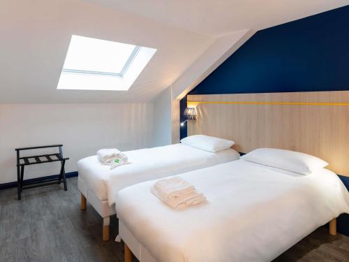 two beds in a hotel room with a skylight at ibis Styles Morlaix in Morlaix