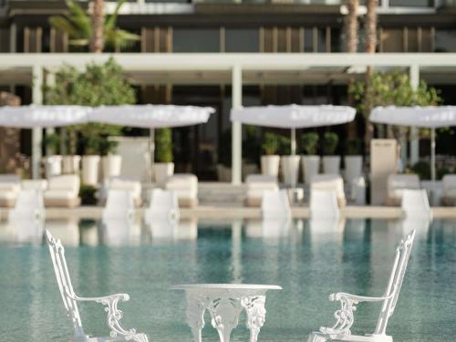 ドバイにあるDelano Dubai at Bluewatersの白い椅子とテーブルが備わるプール